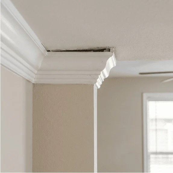 Separation between crown molding and ceiling caused by foundation settlement.
